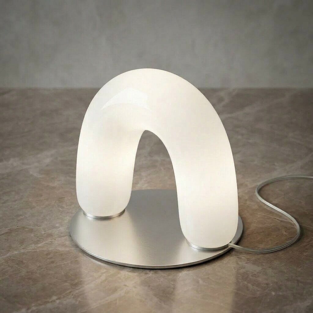The Apo Lamp, a frosted glass arch lamp lit white, on a marble surface